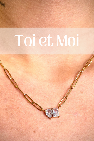 A person wearing a Toi et Moi necklace, which has a paperclip-style chain and a sparkling stone accent.